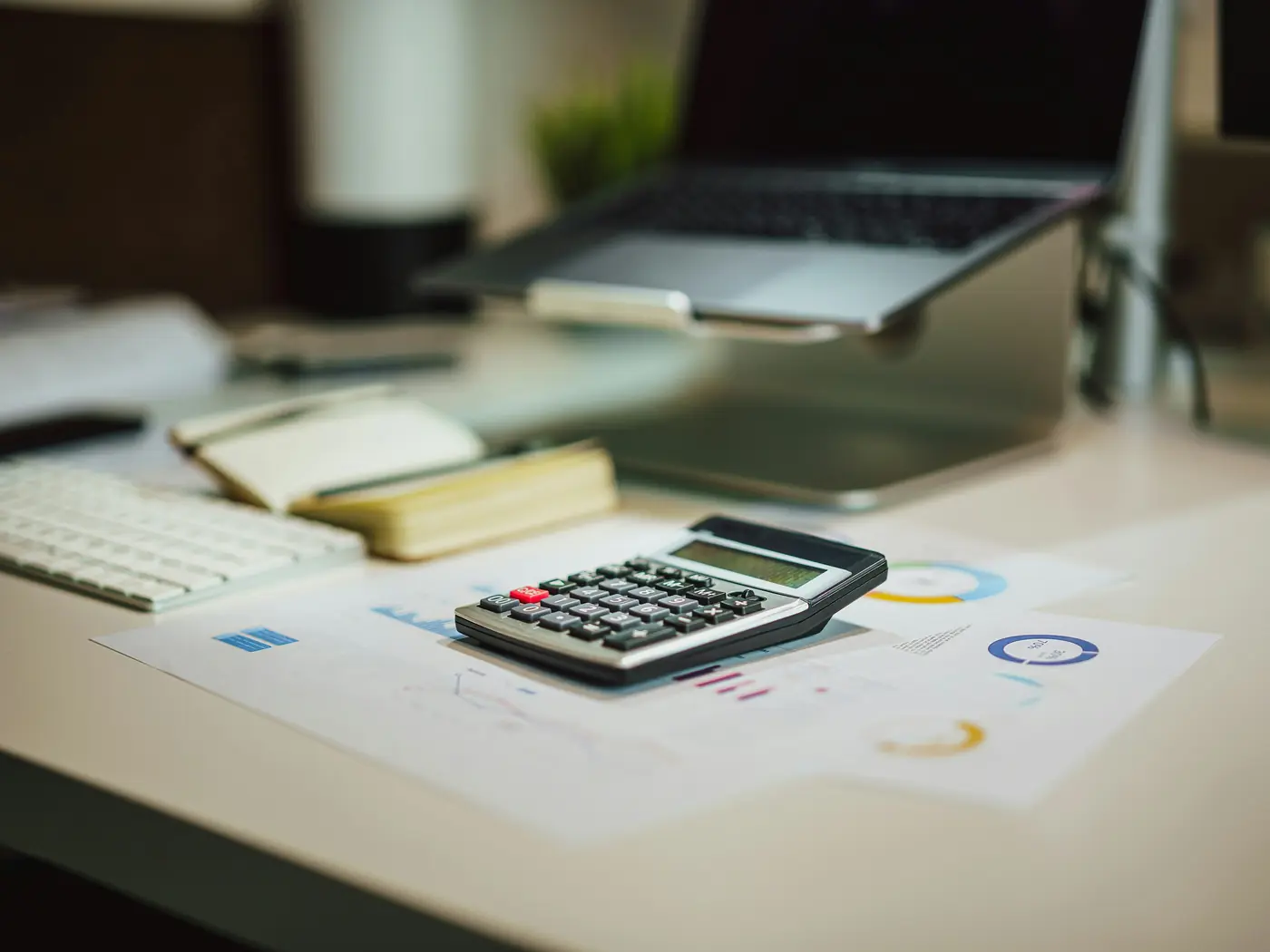 Bureau de travail avec calculatrice, documents chiffrés et ordinateur portable